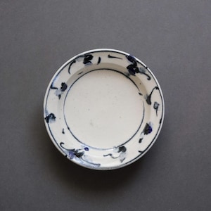 Peut inclure: Petite assiette en céramique blanche ornée d'un motif floral bleu sur le bord. Son design simple et élégant est parfait pour servir des amuse-gueules ou de petites portions. L'assiette est ronde et mesure environ 15 cm de diamètre.