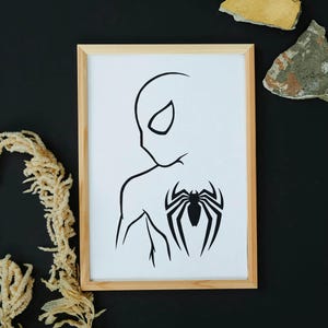 May include: A framed art print featuring a minimalist black and white illustration of a superhero. The artwork depicts the side profile of a character with a spider emblem on the back. The frame is made of light-colored wood.