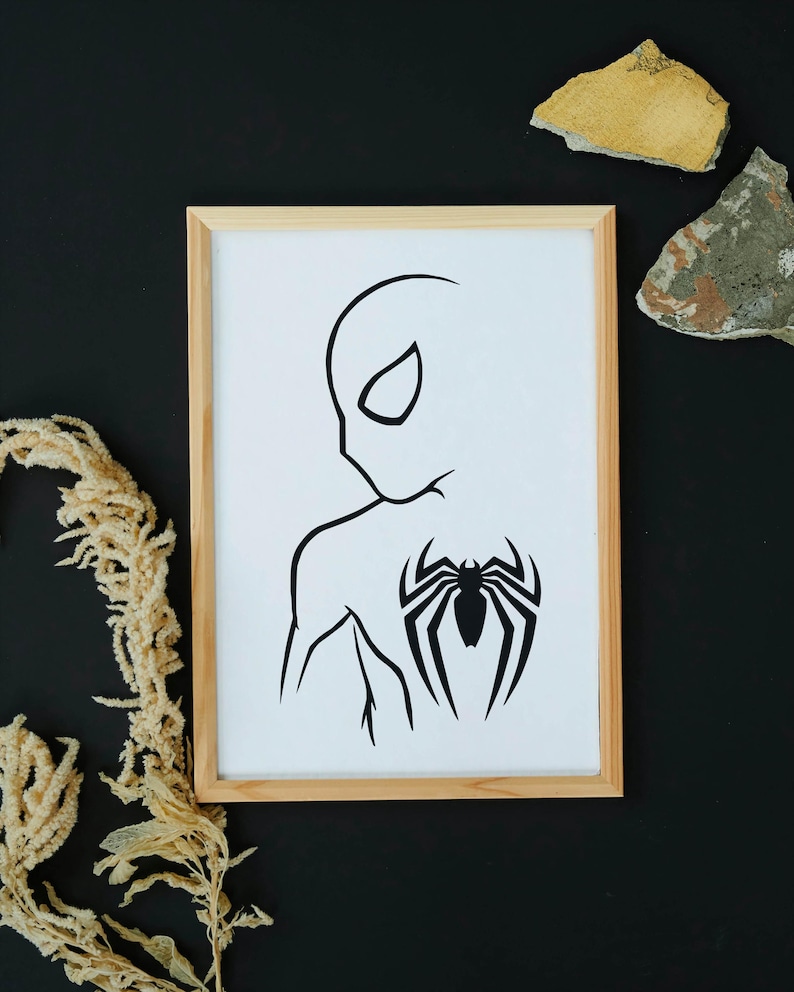 May include: A framed art print featuring a minimalist black and white illustration of a superhero. The artwork depicts the side profile of a character with a spider emblem on the back. The frame is made of light-colored wood.