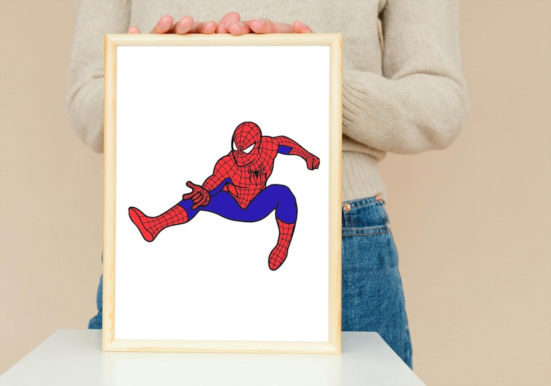 May include: A framed illustration of Spider-Man in a dynamic pose. The superhero is depicted in his classic red and blue suit, with a detailed web pattern on the red sections. The artwork is set against a white background within a light-colored wooden frame.