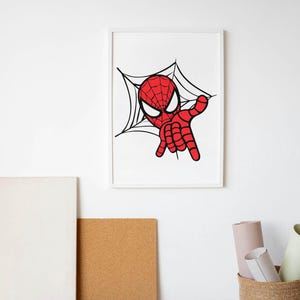 May include: A framed print featuring a cartoon illustration of Spider-Man. The artwork depicts Spider-Man in a red and black suit, with a web design in the background. The image is set against a white wall.