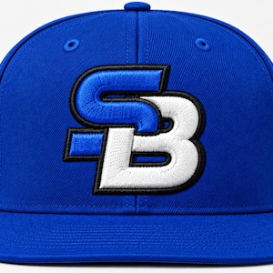 May include: A royal blue baseball cap featuring an embroidered logo on the front. The logo consists of a blue letter S positioned above a white letter B, both outlined in black thread. The cap has a structured crown and a flat brim.