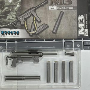 May include: A grey M3 submachine gun model, 1/6 scale, with several magazines and accessories. The packaging features the text "M3" and "ZY2005". The model is presented in a clear plastic tray.