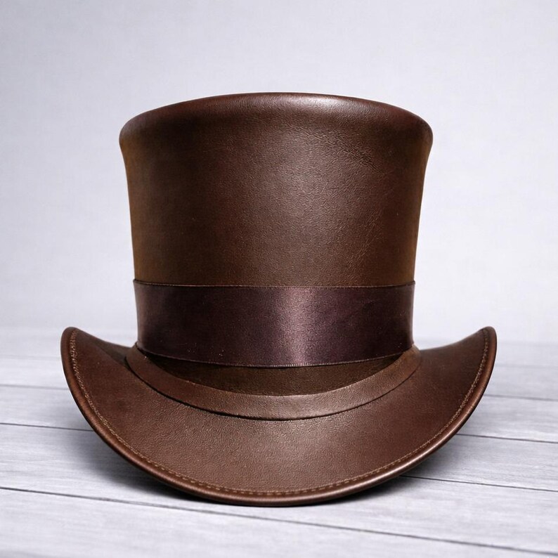 May include: A brown leather top hat with a wide brim and a dark brown ribbon band. The hat has a tall, cylindrical crown and a curved brim. The hat is made of a smooth, shiny leather material.