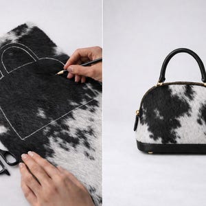 May include: A black and white cowhide handbag with a rounded shape and a black handle. The bag has a black base and gold-colored zipper. The image also shows the process of creating the bag, with a pattern drawn on the cowhide.