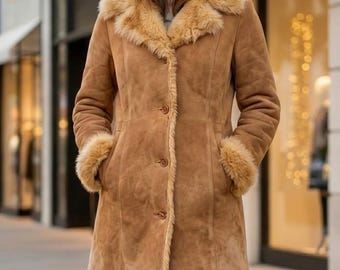 May include: A brown suede coat with a shearling collar and cuffs. The coat has a button-up front and pockets. The shearling trim is a lighter shade of brown than the coat itself. The coat is knee-length and appears to be warm.