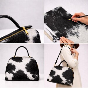 May include: A black and white cowhide handbag with a gold zipper and handle. The bag has a rounded shape and a black handle. The image shows the bag being made, with a pattern being drawn on the cowhide.