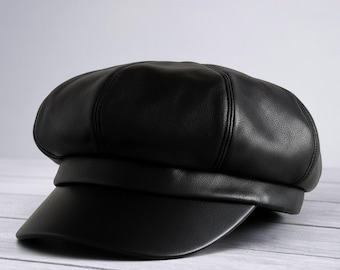 May include: A black leather baker boy hat with a rounded crown and a short, stiff brim. The hat is made of a smooth, shiny material and has a classic, structured design. The hat is a stylish accessory.