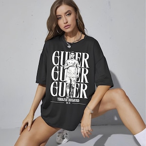 May include: Black oversized t-shirt featuring a graphic of a soccer player with the text "Guler" in large white letters. The shirt also includes the text "Turkish Diamond" and the number 15.