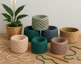 May include: A collection of colorful spools of thick yarn in shades of green, blue, brown, and pink, alongside a woven basket and a potted plant. A wooden crochet hook and loose yarn are also visible, suggesting a crafting theme.