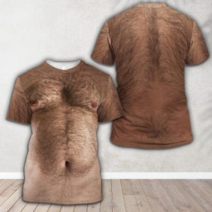 Op de afbeelding: Een t-shirt met korte mouwen voorzien van een realistische, high-definition fotografische print van een behaarde menselijke romp. De voorkant toont een gedetailleerde borst met donker lichaamshaar, twee tepels en een navel, terwijl de achterkant een volledig behaard rugpatroon laat zien.