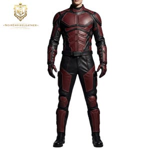 May include: A full-body shot of a person wearing a black and burgundy leather suit. The suit features a high collar, padded chest and shoulder armor, and matching gloves and boots. The Noir Empire Leather logo is in the upper left corner.