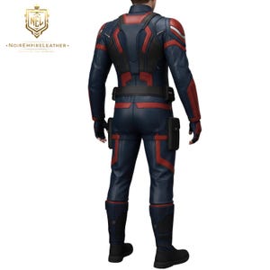 May include: A navy blue and red leather suit with black accents. The suit features a high collar, long sleeves, and a belt. The design includes red stripes and panels on the arms, legs, and torso. The suit has two black pouches on the legs and black boots.