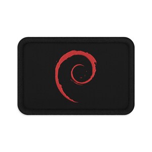 Peut inclure: Un écusson rectangulaire brodé avec un fond en tissu noir et une bordure noire épaisse. Au centre de l'écusson se trouve un motif en spirale rouge qui ressemble à un tourbillon stylisé, avec un aspect texturé créé par les points de broderie.