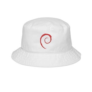 May include: A white bucket hat featuring a red embroidered swirl logo on the front center. The hat has a flat crown, a downward-sloping brim, and a structured fabric construction. The red design consists of a spiral shape with a textured appearance.