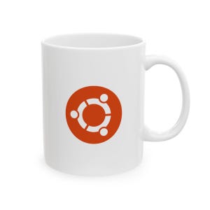 Könnte beinhalten: Ein weißer Keramikbecher mit einem zentrierten, orangefarbenen, kreisförmigen Logo, das drei stilisierte weiße Figuren zeigt, die durch einen Ring verbunden sind. Der Becher hat eine glatte Oberfläche, einen zylindrischen Körper und einen Henkel.