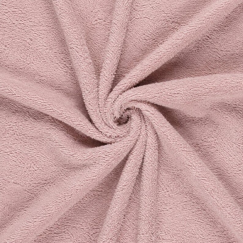 May include: A dusty rose pink towel featuring a dense, looped terry cloth texture. The fabric is arranged in a central spiral pattern, showcasing the soft, absorbent pile of the material with consistent color throughout the entire surface area.