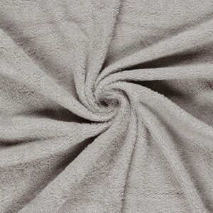 May include: A light gray towel featuring a dense, soft, and plush terry cloth texture. The fabric is arranged in a central spiral pattern, highlighting the consistent pile and the uniform neutral color across the entire surface of the textile.