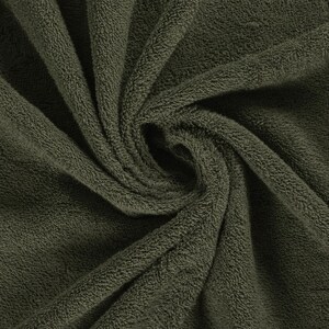 May include: A dark olive green towel featuring a dense, plush terry cloth texture. The fabric is gathered in a central swirl, highlighting the soft, looped pile construction and the deep, uniform color of the textile material throughout the surface.