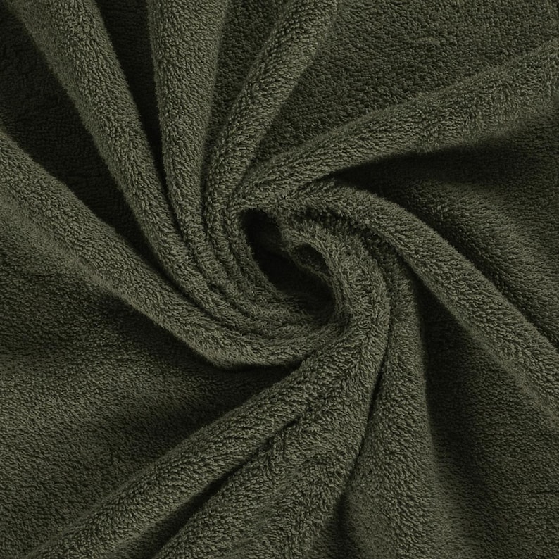 May include: A dark olive green towel featuring a dense, plush terry cloth texture. The fabric is gathered in a central swirl, highlighting the soft, looped pile construction and the deep, uniform color of the textile material throughout the surface.