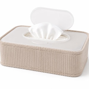 Puede incluir: Una funda rectangular para caja de pañuelos con exterior de tela de pana en color beige claro con textura acanalada vertical. La parte superior es una tapa de plástico blanco translúcido con una abertura central y una tapa abatible que muestra un pañuelo blanco.