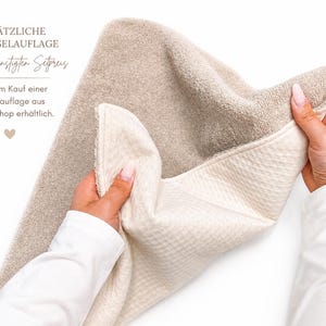 May include: A rectangular changing pad cover featuring a dual-textured design with a soft, beige terry cloth side and a cream-colored, waffle-knit fabric side. The text reads: ZUS&Auml;TZLICHE WECHSELAUFLAGE zum verg&uuml;nstigten Setpreis nur beim Kauf einer Wickelauflage aus meinem Shop erh&auml;ltlich.