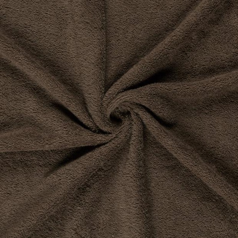 May include: A dark brown fabric with a soft, plush, and fuzzy texture. The material is gathered in the center, creating natural folds and ripples that radiate outward, highlighting the dense, short pile surface of the textile material.