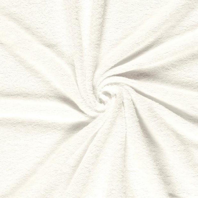 May include: A solid white fabric with a soft, plush, and fuzzy texture. The material is arranged in a central spiral pattern, creating deep folds and shadows that radiate outward from the center, highlighting the dense, short pile of the textile.