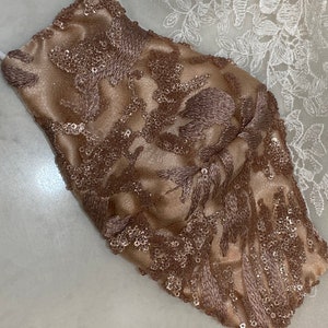 May include: A brown face mask with a floral design and sequins.