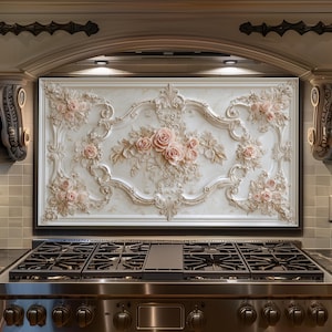 Peut inclure: Hotte de cuisine décorative avec un motif floral en relief blanc et crème et des roses roses. La hotte est encadrée en noir et se trouve au-dessus d'une cuisinière à gaz en acier inoxydable.