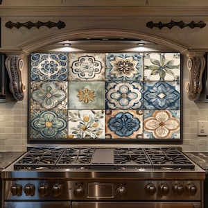 May include: A decorative backsplash featuring a grid of twelve square tiles with floral and geometric patterns in shades of blue, beige, and green. The tiles are mounted above a stainless steel gas range in a kitchen setting.