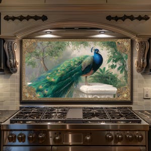 May include: A framed artwork depicting a peacock with striking blue and green feathers. The peacock is perched on a white stone structure, set against a backdrop of foliage. The artwork is framed in gold and is mounted above a stainless steel gas cooker.