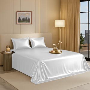 Peut inclure: Un lit avec des draps en satin blanc et deux taies d'oreiller assorties. Le lit est fait et prêt à l'emploi. Une petite table de chevet avec une bougie et une image d'arbres sur le mur sont également visibles.