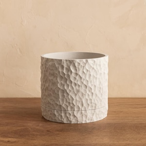 Vaso orgânico moderno com textura de mármore esculpido e bandeja coletora de gotas oculta.