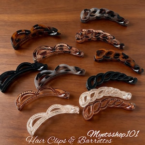Peut inclure: Diverses pinces à cheveux et barrettes de style banane, de couleurs et motifs variés. Les pinces sont en plastique et présentent un design incurvé. Les couleurs incluent le noir, le marron, l'écaille de tortue et le transparent. Le texte "Hair Clips & Barrettes" et "Myetsshop101" sont visibles.