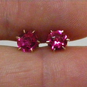 May include: A pair of pink gemstone earrings with a prong setting.