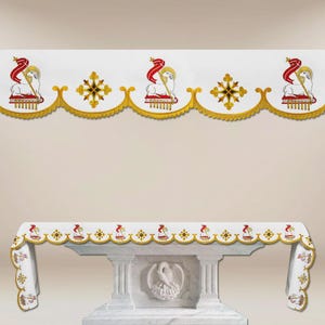 May include: White altar cloth with gold trim and embroidered lamb and cross designs. The cloth is draped over a white marble altar. The top of the altar has a matching valance with the same lamb and cross design.