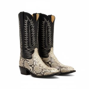 May include: A pair of cowboy boots with a snakeskin pattern on the foot and a black leather shaft. The shaft features decorative stitching in a silver color. The boots have a pointed toe and a stacked heel.