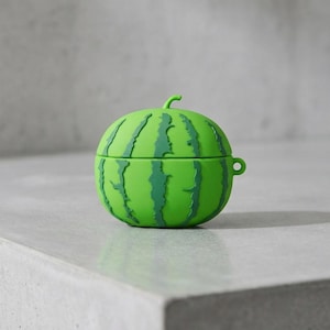 Könnte beinhalten: Eine hellgrüne, wassermelonenförmige Hülle mit dunkelgrünen Streifen. Die Hülle hat einen kleinen Stiel oben und eine Schlaufe an der Seite. Sie ist für kleine elektronische Geräte konzipiert.