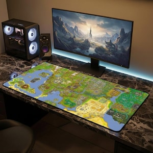 以下が含まれることがあります： 緑、青、黄色の詳細な地図が描かれた、大きな長方形のマウスパッド。マウスパッドは、風景を表示するコンピューターモニター、コンピュータータワー、スピーカーのある机の上にあります。