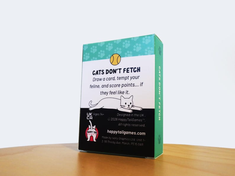 May include: A rectangular game box titled CATS DON'T FETCH with a teal top featuring paw prints, a yellow ball icon, and a white center panel. The text reads: Draw a card, tempt your feline, and score points... if they feel like it. Includes a cat illustration, the Happy Tail Games logo, and copyright information.