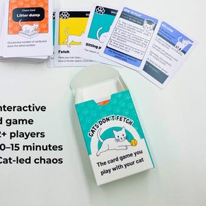 May include: A card game titled Cats Don't Fetch with a teal and white box featuring a white cat illustration. The set includes a deck of cards with various cat-themed instructions, including a Chaos Card labeled Litter dump and a How to Play card.