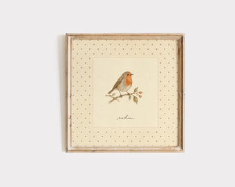 May include: A square framed wall art piece featuring a watercolor illustration of a robin perched on a branch. The background is a cream-colored paper with a dark brown polka dot pattern. The word robin is written in cursive script below the bird.