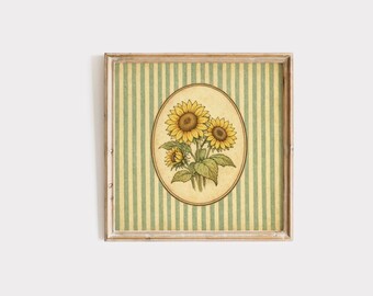 May include: A framed print featuring a botanical illustration of sunflowers. The sunflowers are in an oval frame against a striped background of green and cream. The frame is a light wood color.