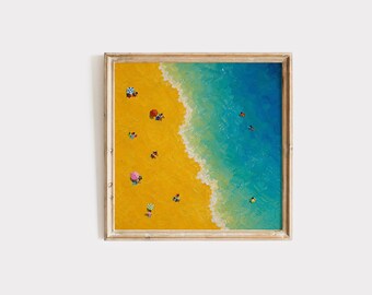 May include: A square framed painting depicting an aerial view of a beach with vibrant yellow sand and turquoise ocean water. Small figures are scattered across the sand and in the water, with colorful umbrellas dotting the shoreline.