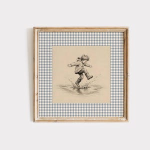 Pode incluir: Uma impressão de arte emoldurada com uma ilustração a tinta preta e branca de uma criança a saltar para uma poça. A obra está colocada sobre um fundo de xadrez vichy azul claro e branco dentro de uma moldura de madeira clara.