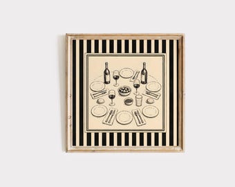 May include: A square framed wall art print featuring a black and white line drawing of a dinner table setting with plates, wine bottles, glasses, and bowls of food, centered on a cream background with a bold black and white vertical striped border.