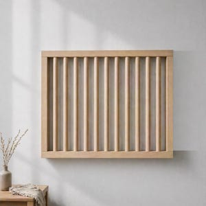 Könnte beinhalten: Ein rechteckiges Wandpaneel aus Holz mit vertikalen Dübeln. Das Paneel besteht aus hellfarbigem Holz und ist an einer weißen Wand montiert. Das Design ist schlicht und modern, geeignet für die Inneneinrichtung.
