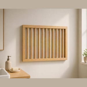 Könnte beinhalten: Ein helles, an der Wand montiertes Holzregal mit vertikalen Dübeln. Das Regal ist rechteckig und scheint aus Naturholz zu bestehen. Das Design ist schlicht und minimalistisch, geeignet für ein Badezimmer oder einen anderen Innenraum.