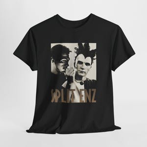 May include: Black t-shirt with a sepia-toned image of two men with striking makeup. The band name "SPLIT ENZ" is printed in brown. The shirt has a crew neck and short sleeves.